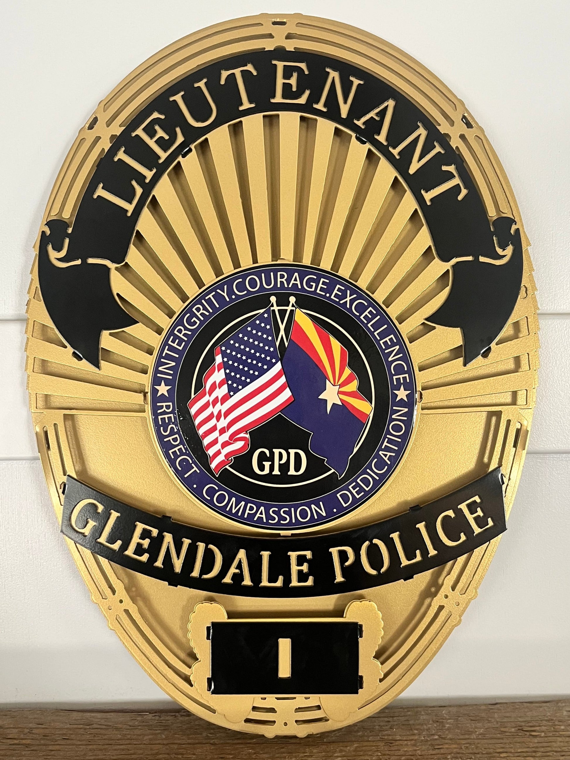 Gold Glendale Police badge with American flag on a white wall