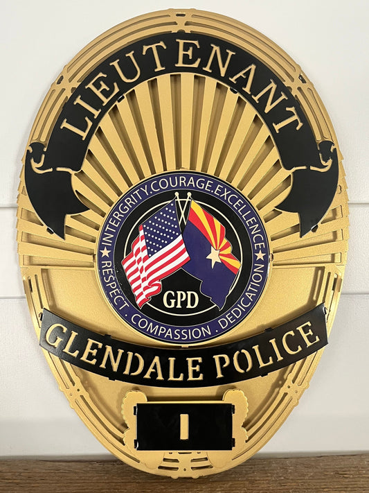 Gold Glendale Police badge with American flag on a white wall