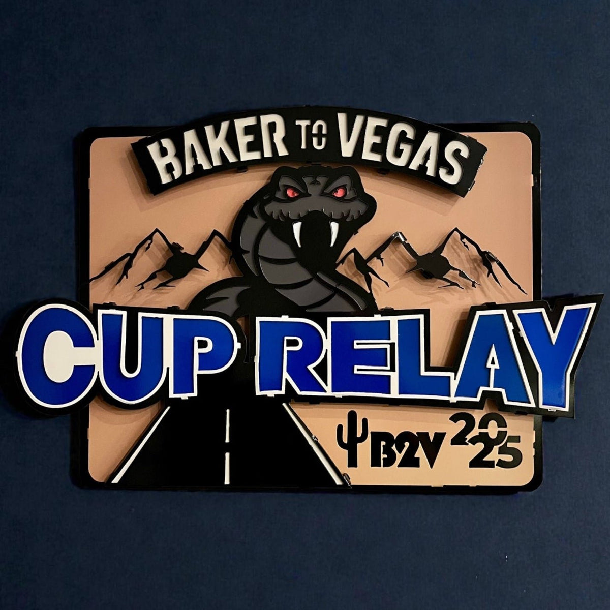 Cup Relay sign with blue lettering against a dark background, Baker to Vegas Challenge Cup Relay Sign by IRONiNK.