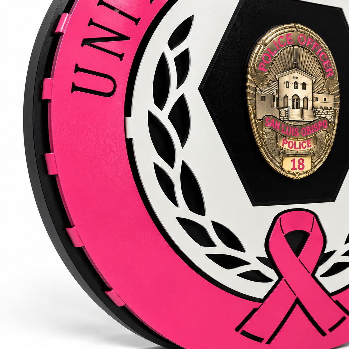 Angled view showing the layered pink, white and black aluminum construction around the badge panel