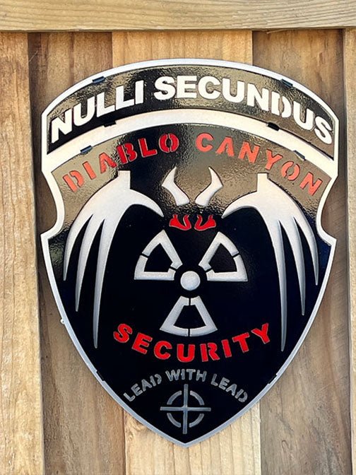 Black silver and red security shield on a wooden wall, Diablo Canyon Security by IRONiNK.