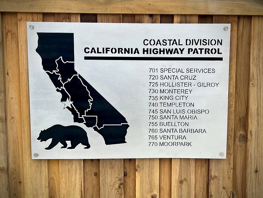 Silver Coastal Division sign on a wooden fence.