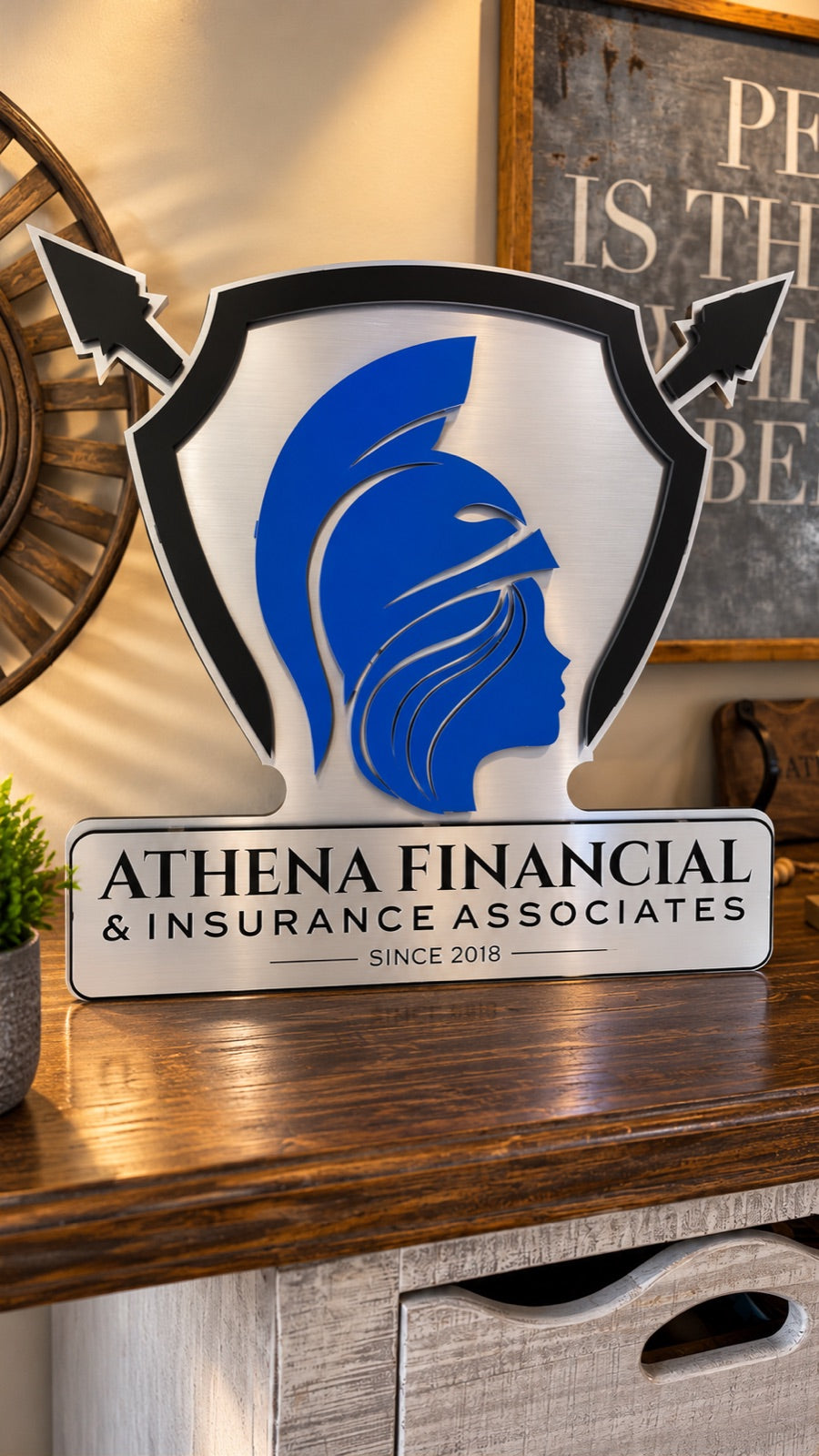 Athena Financial and Insurance Associates shield-shaped sign in brushed aluminum, black and blue with crossed arrows