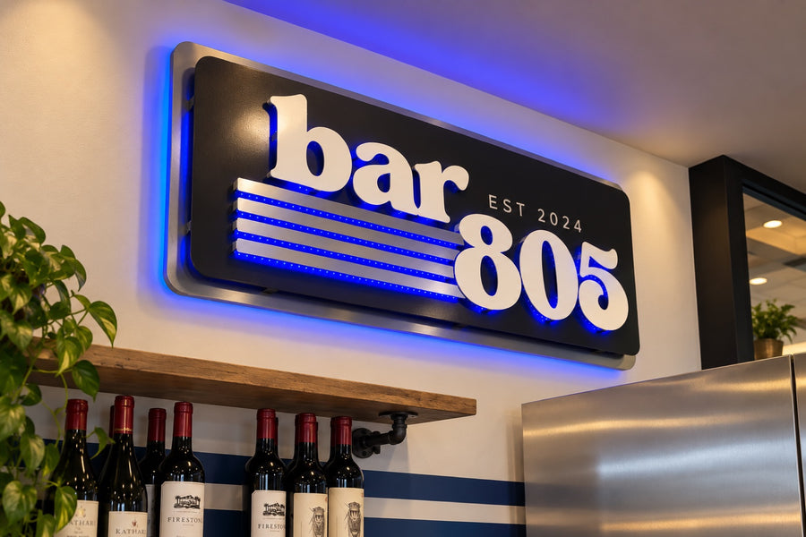 Bar 805 illuminated wall sign with white raised lettering and blue backlighting over a wine shelf