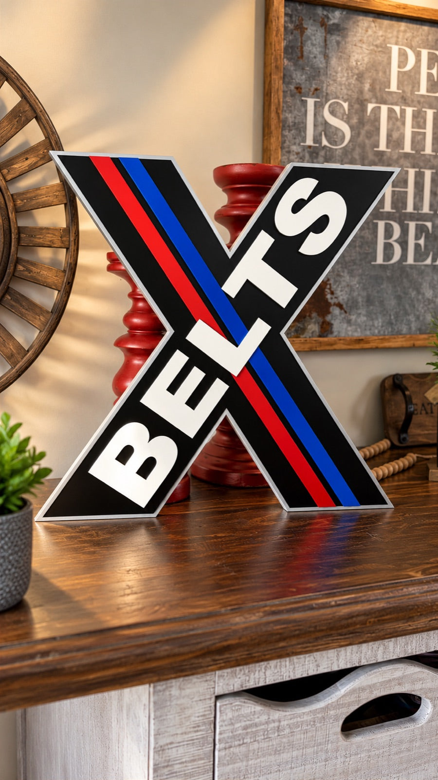 X Belts custom cut metal logo sign shaped like an X with red and blue stripes and raised white lettering